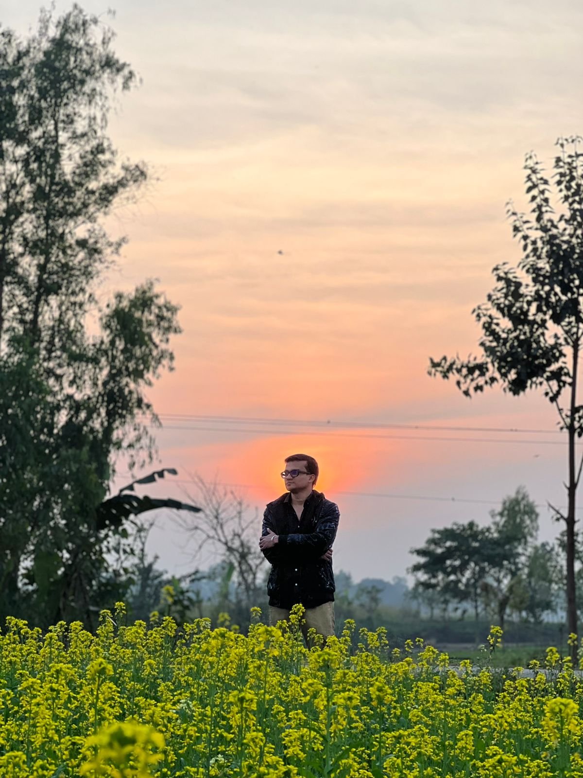 Freelancer Tamal standing in a yellow mustard-flower field at sunset in Rangpur Division, Bangladesh