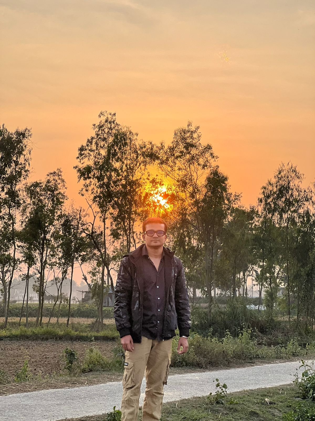 Freelancer Tamal walking at golden hour on a quiet rural road through eucalyptus trees outside Rangpur, Bangladesh